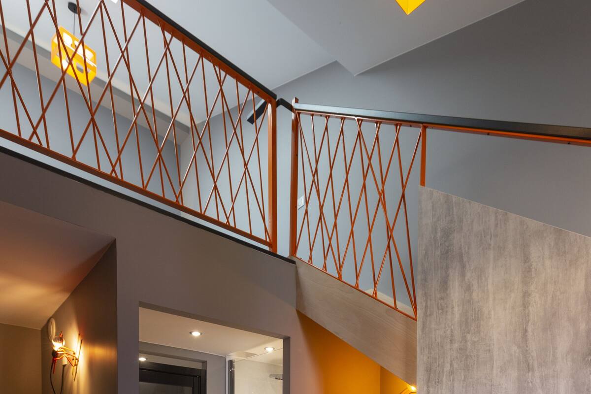 Un intérieur moderne avec un escalier, un téléviseur à écran plat fixé au mur et une petite table ronde.