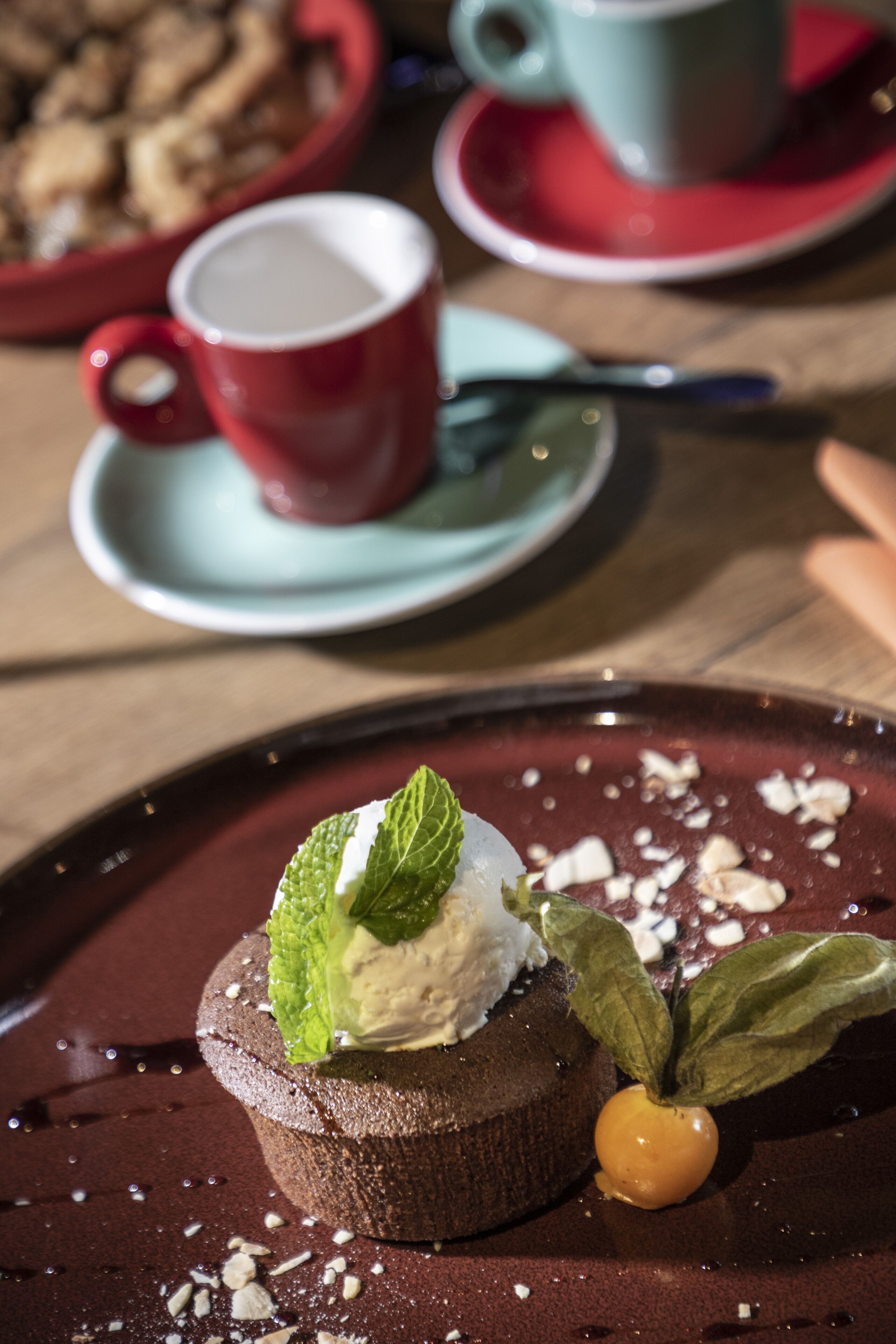 Ein Dessert auf einem Teller, im Hintergrund eine Tasse und ein Untertasse.