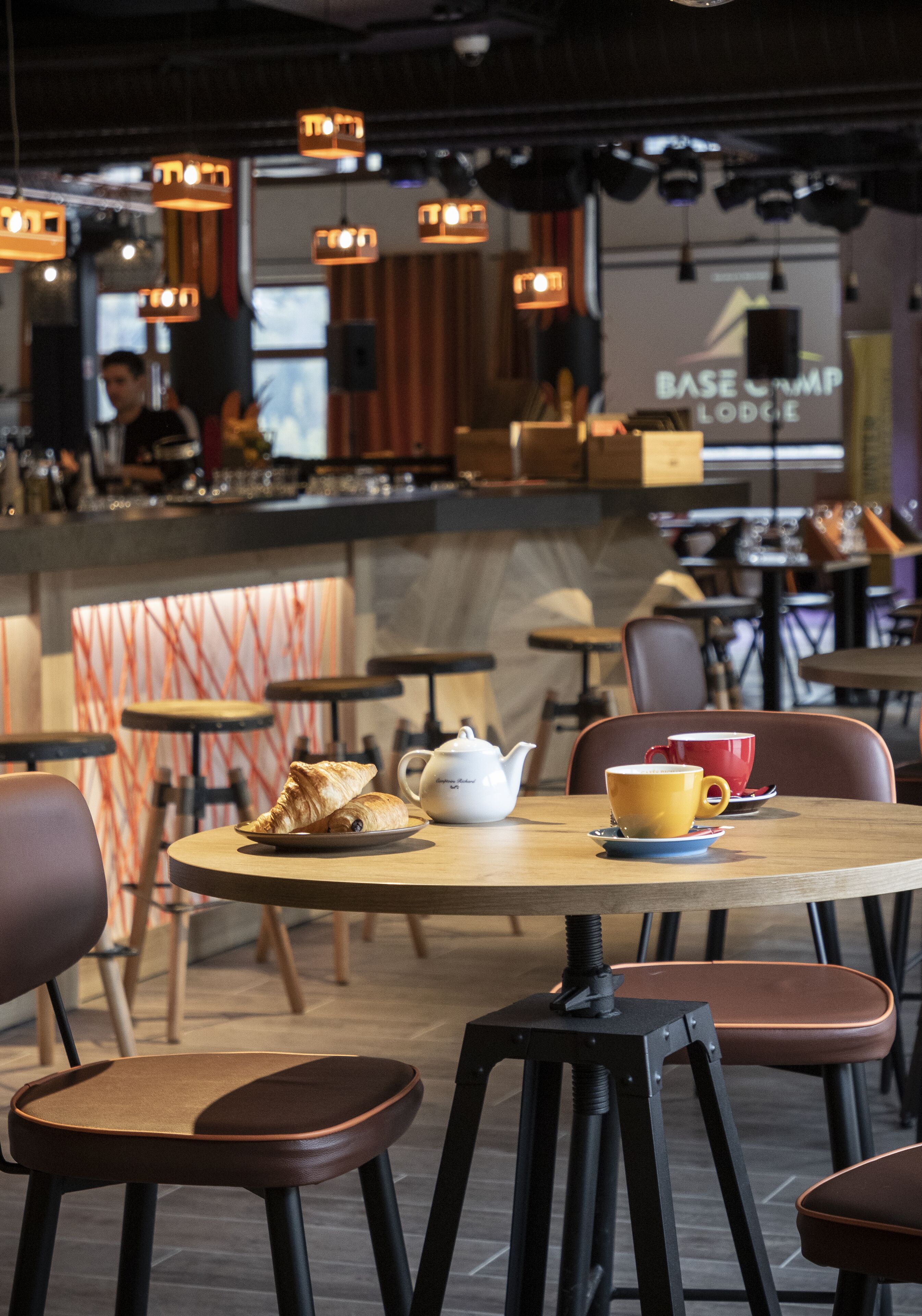 Un café moderno con mesas y sillas redondas, y una zona de bar.
