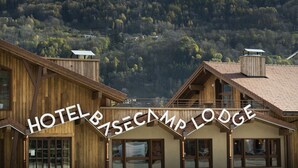 Una cabaña de madera con vistas a una montaña nevada y colinas boscosas.