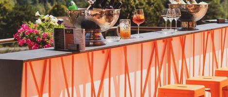 A bar area with a champagne bucket, glasses, and bottles, set against a backdrop of trees.
