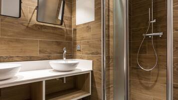 Un baño moderno con ducha envuelta en vidrio, tocador doble y revestimiento de madera.