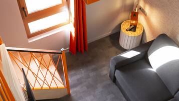 A modern living room with a grey sofa, a wooden staircase, and a hanging orange light fixture.