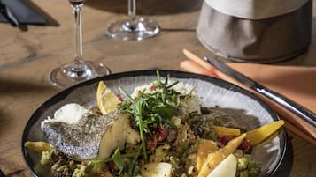 Une table à manger avec une assiette de nourriture, des verres à vin et une bouteille de vin.