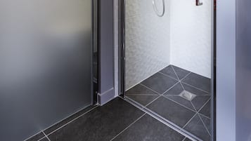 Una doccia moderna con porta in vetro, soffione a mano e pannello di controllo a parete.