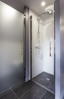 Una doccia moderna con porta in vetro, soffione a mano e pannello di controllo a parete.