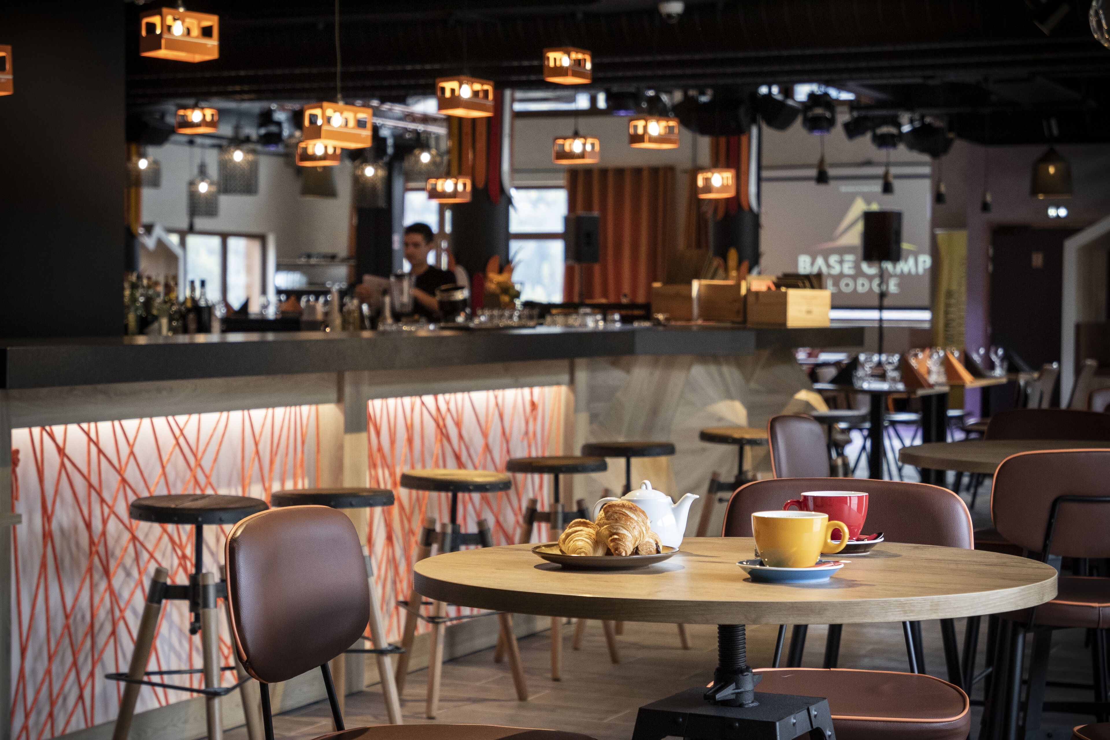 A modern cafe interior with round tables, chairs, and a bar area.