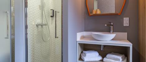 A modern bathroom with a glass-enclosed shower, a white sink with a vessel basin, and a wooden vanity.