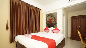 Een slaapkamer met een bed, gordijnen, een kledingkast en een stoel.