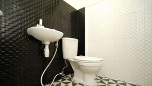 Een badkamer met een zwart-wit betegelde vloer, een witte wastafel en een toilet.