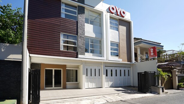 Een modern, twee verdiepingen hoog gebouw met een opvallend 'OYO'-bord, grote ramen en een hekwerkentree.