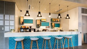 Un área de bar moderna con encimera blanca, salpicadero de azulejos azules y taburetes de madera.