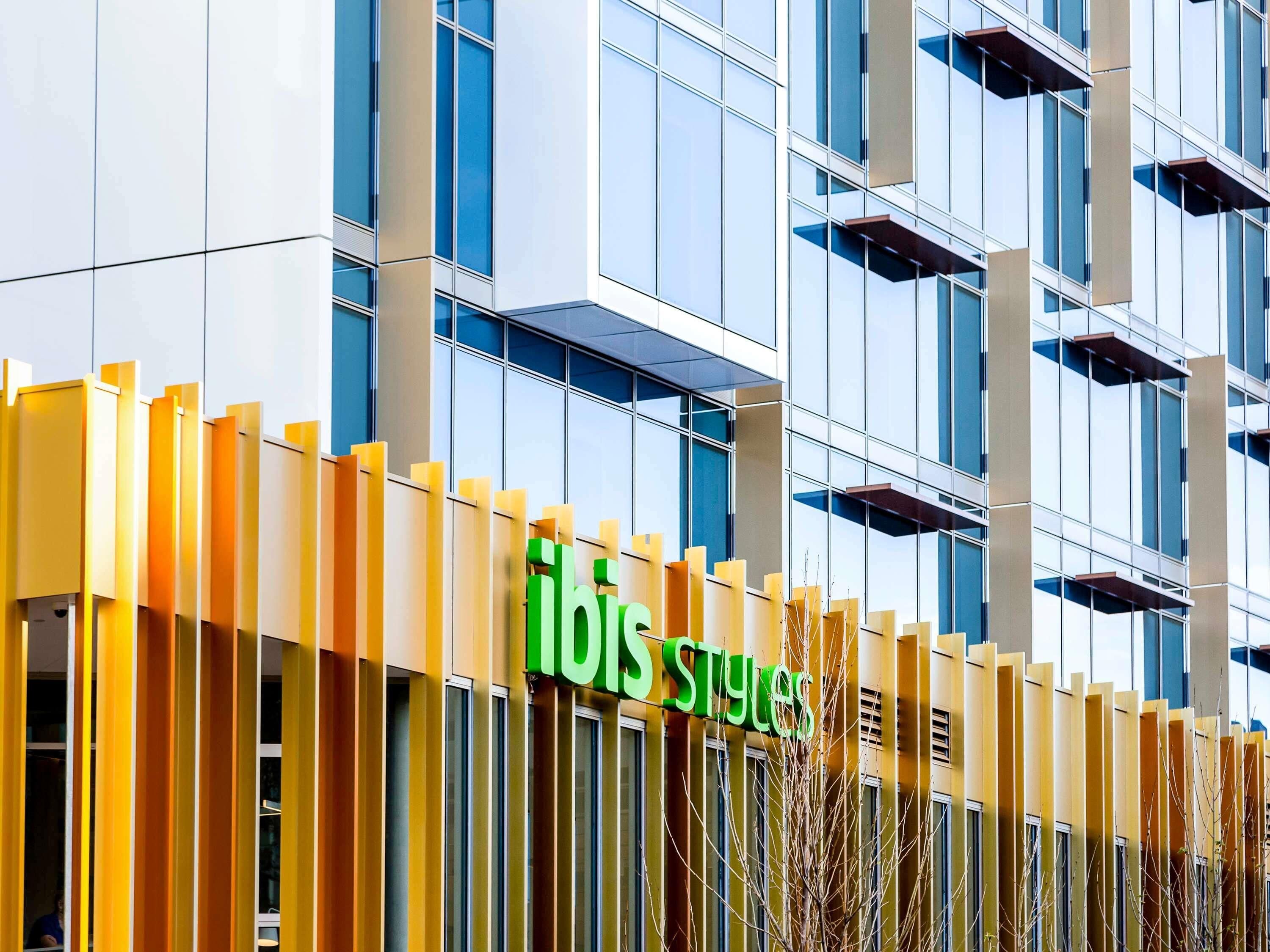 Un edificio moderno con un llamativo letrero de 'ibis Styles'.