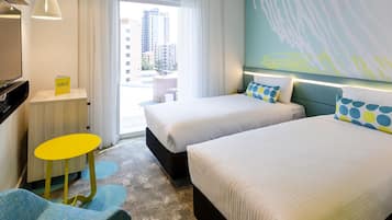 Habitación de hotel con dos camas, un escritorio, una silla y vistas a edificios.