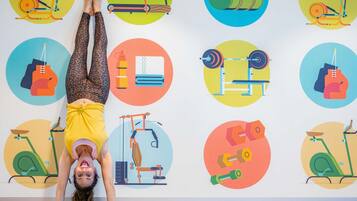A person performing a yoga pose on a mat with a wall displaying various fitness equipment illustrations.