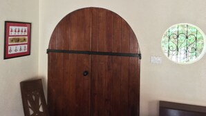 Una puerta de madera con un picaporte de metal, un cuadro en la pared con copas de vino, y un ventanal circular con un diseño decorativo.