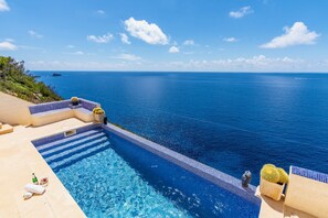 A pool with a view of the ocean, a cactus, and a stone statue. - House with beautiful views to the sea, front line with pool and several terraces (El Toro)