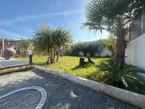 Un jardín con palmeras, una terraza de madera y una placa metálica.
