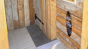 Un intérieur en bois agrémenté d’une œuvre d’art encadrée, d’une affiche et d’une décoration sur le thème du surf.