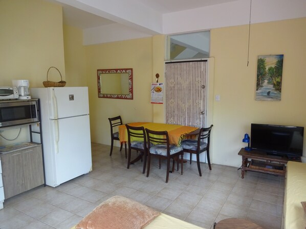 Un espacio habitable pequeño con cocina, mesa de comedor y televisión.