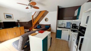 A compact living space with a sofa, a small dining table, a kitchenette, and a staircase. - Holiday house for 4 people, 2 bedrooms, new conservatory, in a secured residence with pool LE... (PORTIRAGNES)
