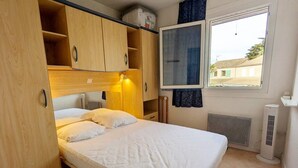 A compact bedroom with a single bed, wooden wardrobe, and a window with a view of buildings outside. - Holiday house for 4 people, 2 bedrooms, new conservatory, in a secured residence with pool LE... (PORTIRAGNES)