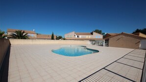 A swimming pool with a tiled deck, surrounded by buildings with tiled roofs. - Holiday house for 4 people, 2 bedrooms, new conservatory, in a secured residence with pool LE... (PORTIRAGNES)