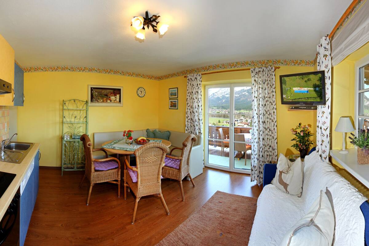 A cozy kitchen with a dining area, a sofa, and a TV.