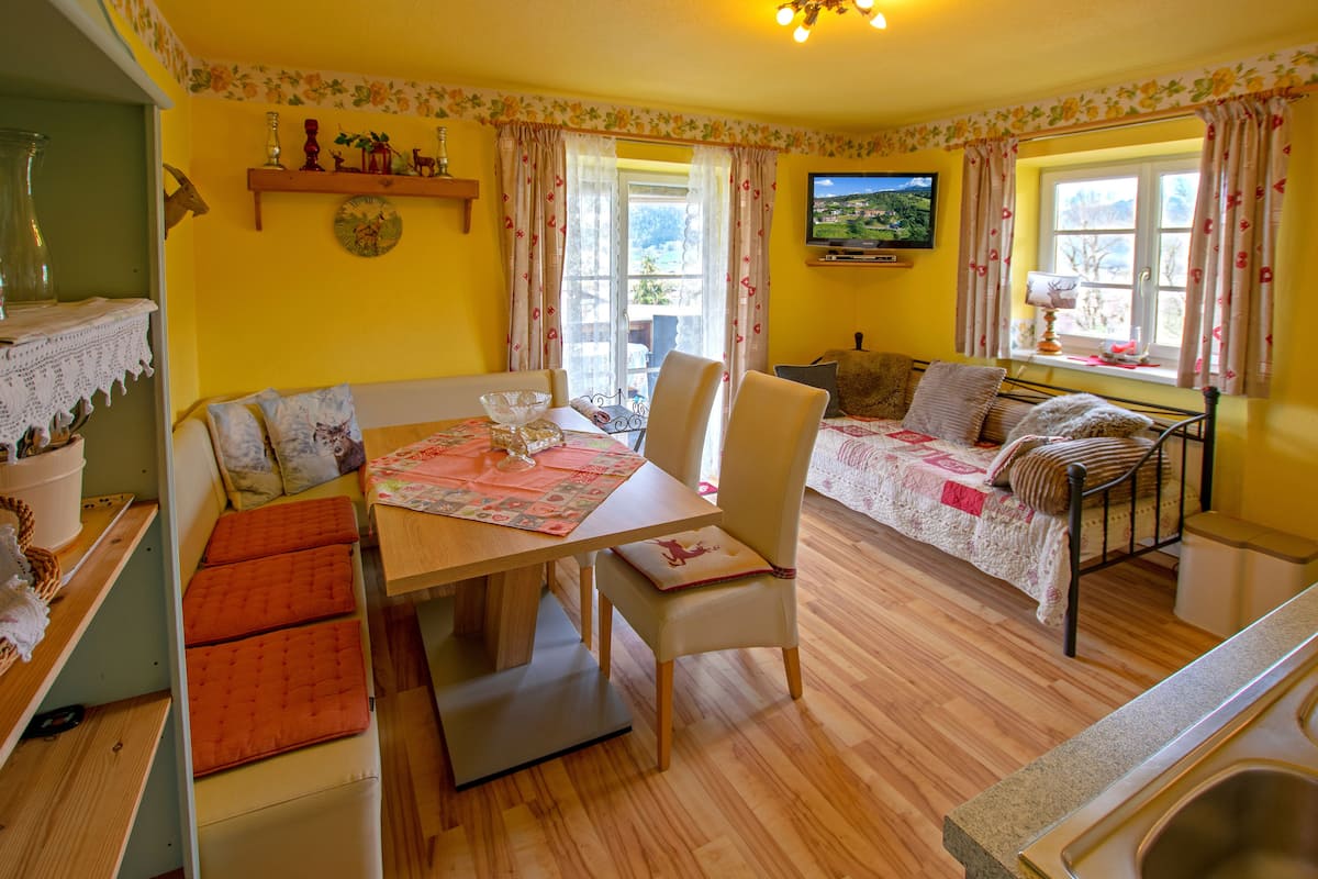 A cozy room with a dining table, chairs, a sofa, and a TV.