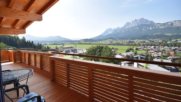 Una terraza de madera con vistas a un pueblo y montañas.
