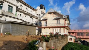 Um edifício residencial de vários andares com varandas, um reservatório de água e um jardim com vasos de plantas e flores.