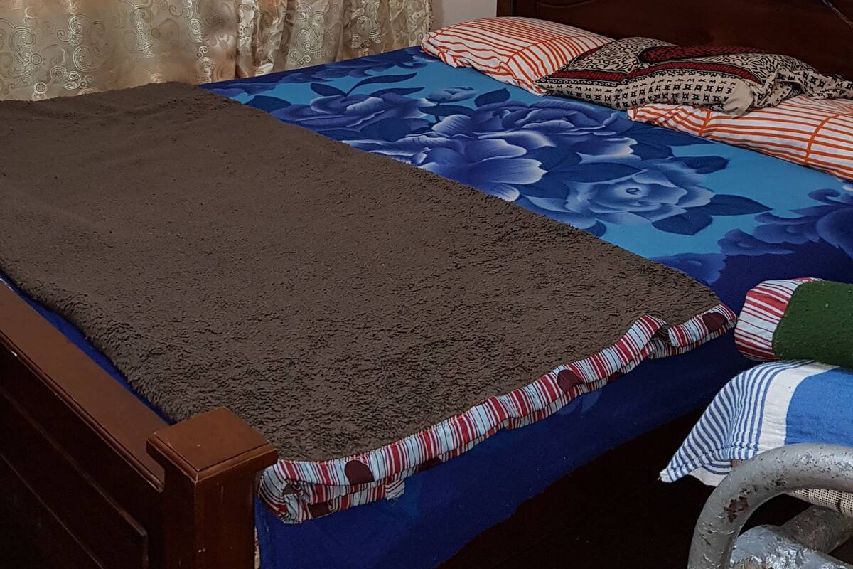 Une chambre à coucher avec un lit en bois, des rideaux à motifs et une couvre-lit à fleurs bleues.