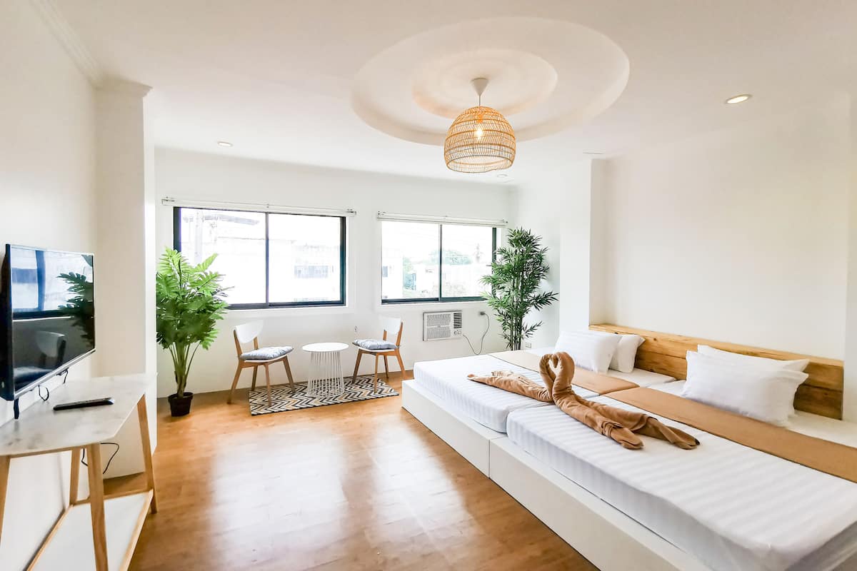 Une chambre moderne et bien éclairée, équipée d’un lit, d’un coin salon et d’un téléviseur.