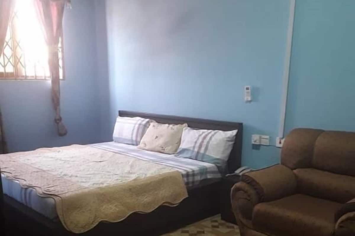 A bedroom with a bed, a brown leather chair, and a patterned floor.