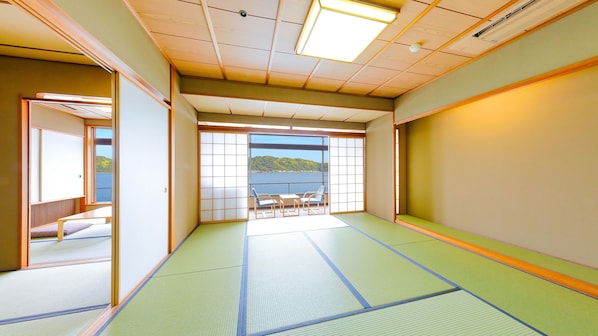 A traditional Japanese room with tatami flooring, sliding doors, and a view of a body of water. - Ooedo Onsen Monogatari Nanki Kushimoto (Kushimoto)