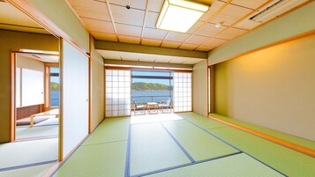 Una habitación tradicional japonesa con suelo de tatami, puertas correderas y vista a un cuerpo de agua.
