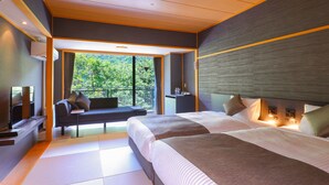 Ein modernes Hotelzimmer mit einem großen Bett, einer Couch, einem Fernseher und einem Balkon mit Blick auf den Wald.