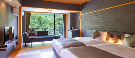 A modern hotel room with a large bed, a sofa, a TV, and a balcony with a view of the forest.