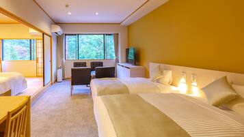 A hotel room with two beds, a desk, a chair, a TV, and large windows with a view of trees.