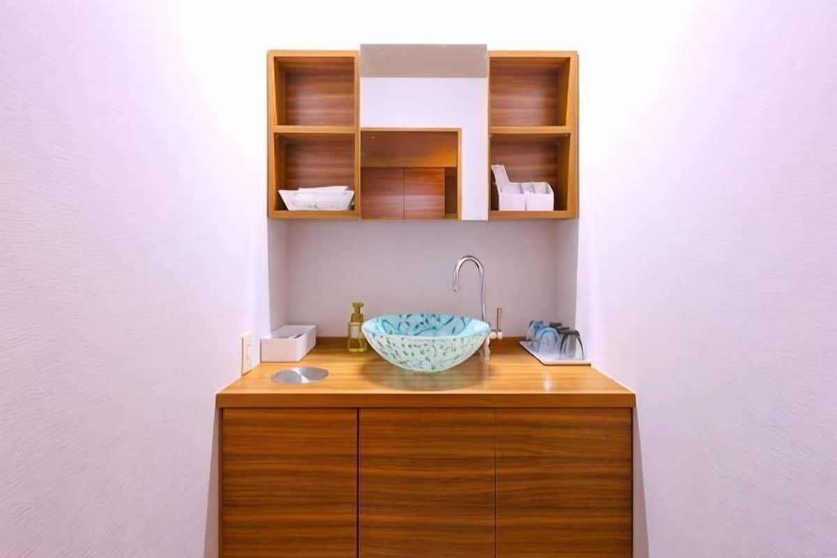 Un tocador de madera con lavabo, un espejo y estantes arriba.
