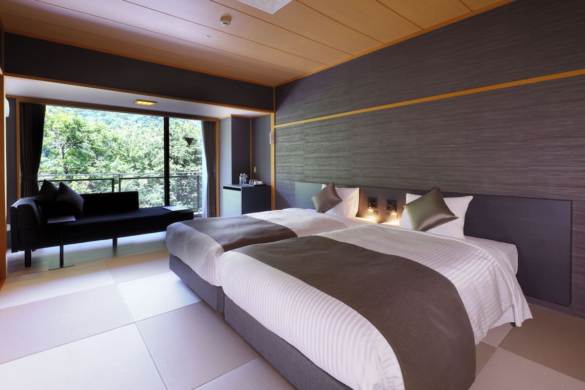 Une chambre d’hôtel moderne avec un grand lit, un coin salon offrant une belle vue et une grande fenêtre.