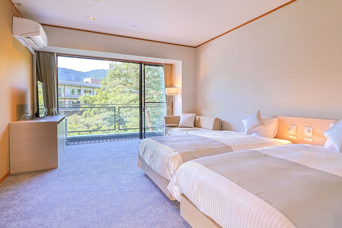 Une chambre d’hôtel avec un grand lit, un bureau et un balcon offrant une vue sur la ville.