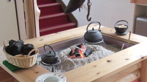 A wooden table with a built-in fire pit, a kettle, a teapot, and a basket of charcoal. - Shinseikan (Nishiwaga)