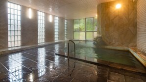 An indoor swimming pool with a tiled floor, a metal ladder, and a wooden wall with a geometric pattern. - Shinseikan (Nishiwaga)