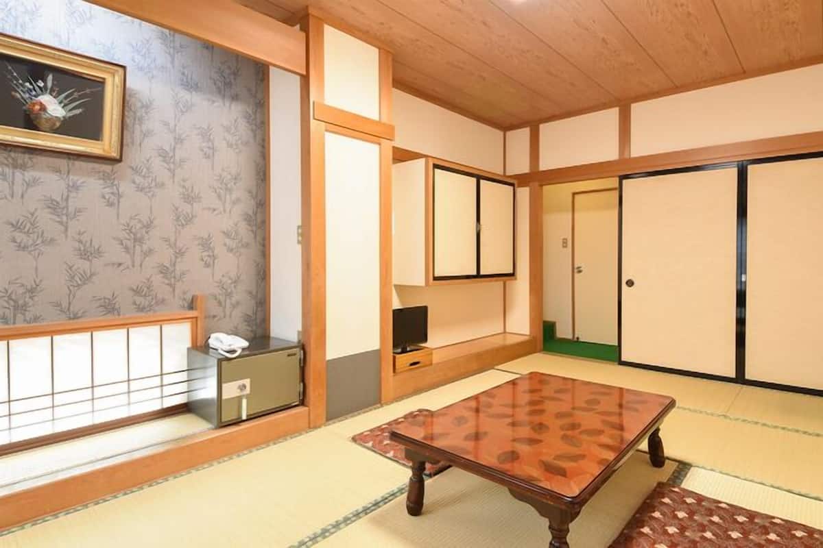A traditional Japanese room with tatami flooring, a low wooden table, sliding doors, and a small cabinet with a telephone.