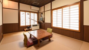 A traditional Japanese room with tatami flooring, a wooden table, a television, and sliding doors with paper screens. - Shinseikan (Nishiwaga)