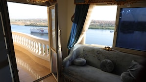 A room with a view of a river and a cityscape, a balcony with a railing, and a sofa with decorative pillows. - Luxurious and Panoramic Nile view. (Cairo)