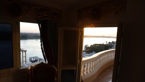 A room with a view of a river and a bridge, a balcony with a balustrade, and a chair. - Luxurious and Panoramic Nile view. (Cairo)