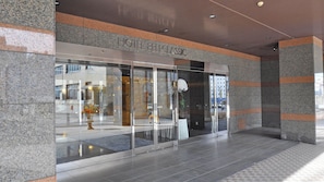 Fachada de hotel de vidrio, con un letrero que dice 'HOTEL CLASSIC' y piso de baldosas.