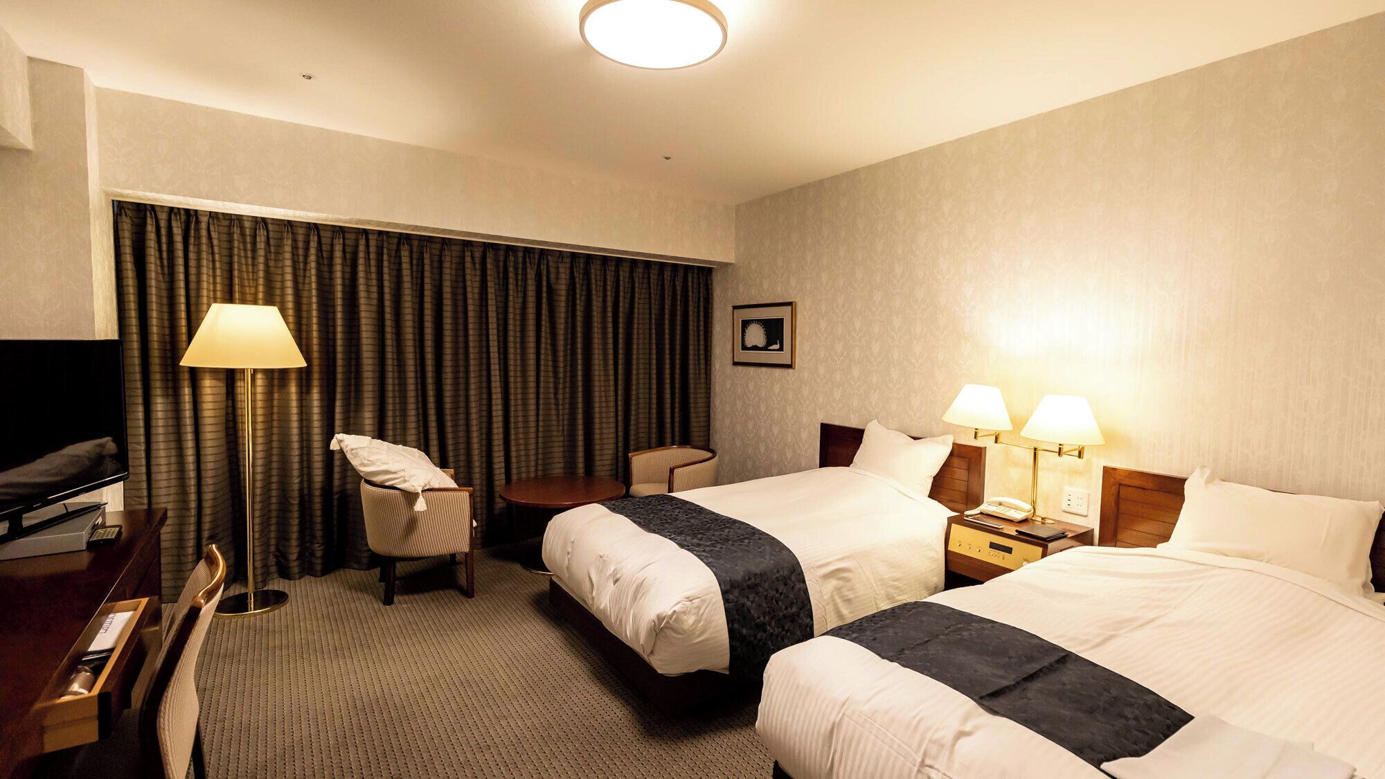 Een hotelkamer met twee bedden, een bureau, een stoel, een televisie en een lamp.